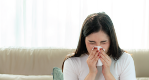 woman inside on couch blowing nose due to indoor air pollutants