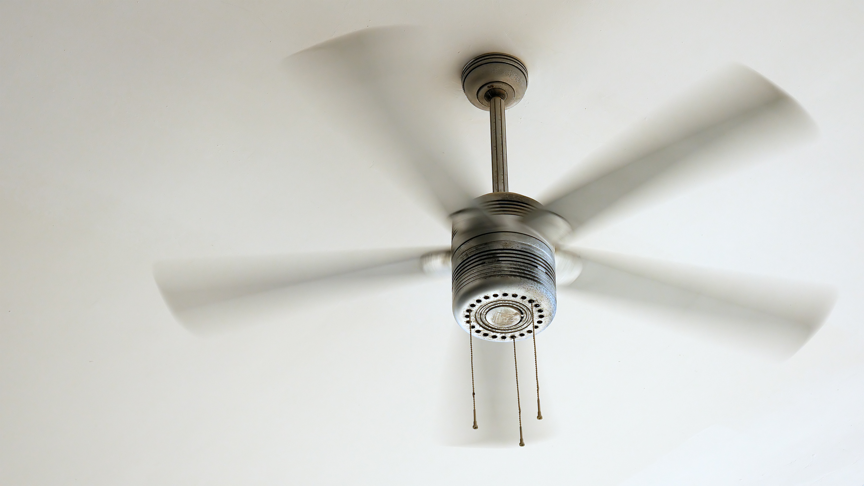 Ceiling fan is rotating at the ceiling of the room. Electric climate 