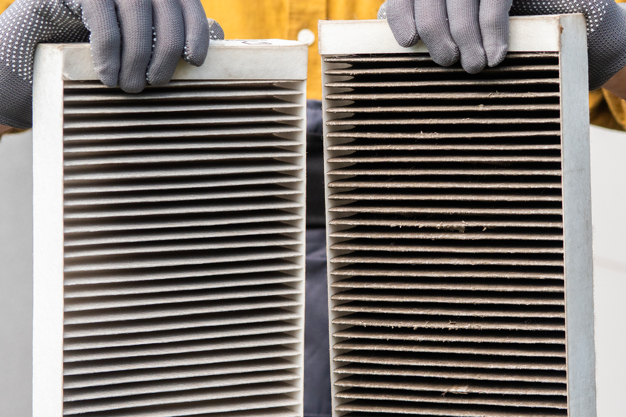 Worker holding two dirty air filters from a home ventilation system. stock photo