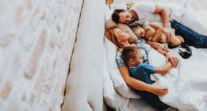 Happy beloved family sleeping together in bed - breathing purified air