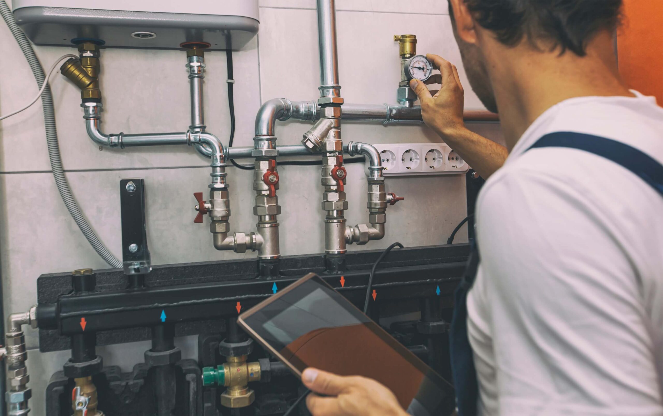 The technician checking the heating system in the boiler room with the tablet in his hand