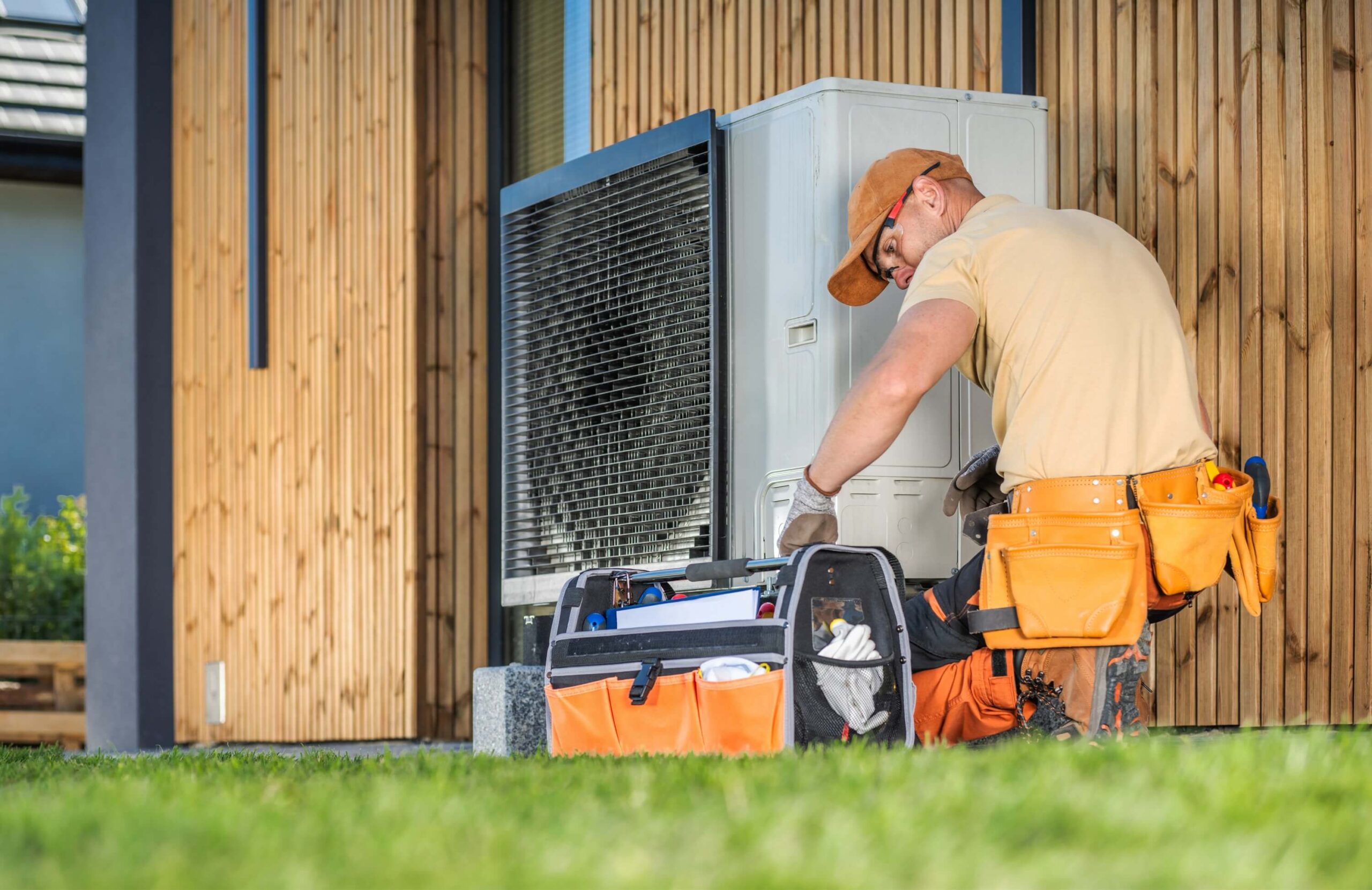 Worker working on a modern heat pump outside a home