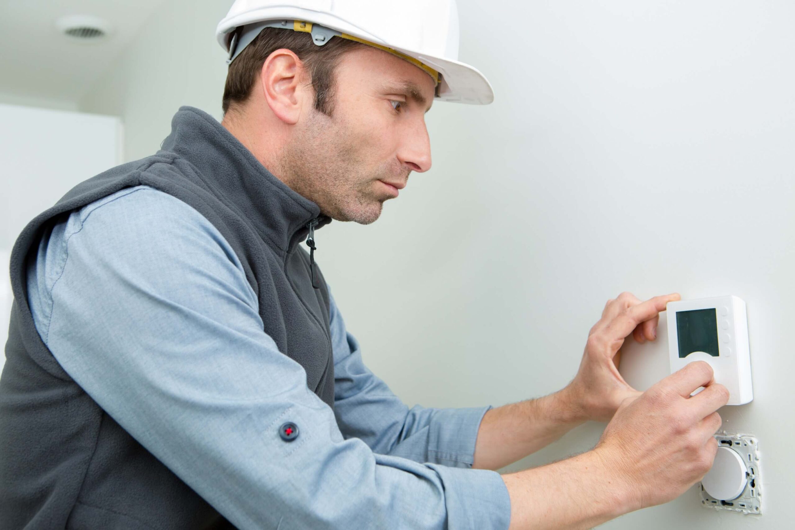 Male worker installing thermostat