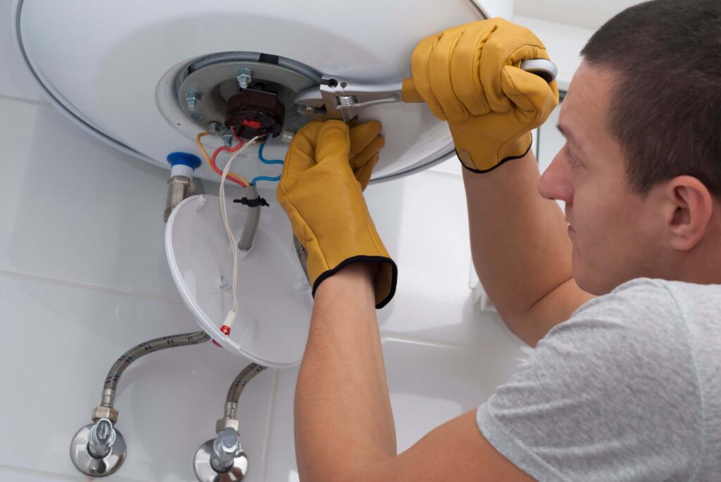 The repairman with a wrench in his hand tightens the nuts of an electric boiler